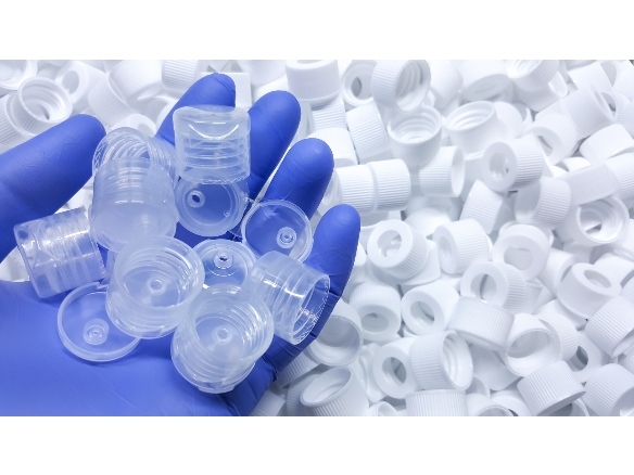 Hand holding many bottle caps for dispensers in injection molding plastics