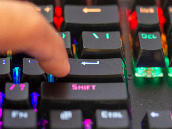 finger touching a long travel keyboard on a computer